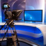 TV studio with camera and empty anchor desk.