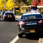 Police cars and school buses on a road.