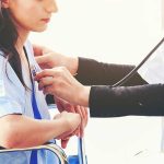 Doctor checking patient's heartbeat with stethoscope.