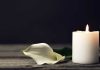 white candle with a white flower laying next to it