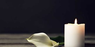 white candle with a white flower laying next to it