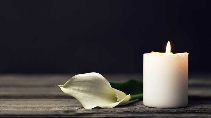 white candle with a white flower laying next to it