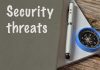 Security threats text beside pen and compass on notebook.