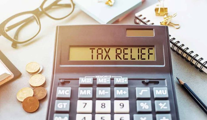 Calculator display reads "TAX RELIEF" amidst coins and glasses.