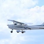 Small plane flying in a cloudy sky.