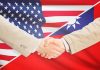 Two people shaking hands with USA, Taiwan flags.