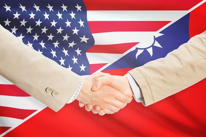 Two people shaking hands with USA, Taiwan flags.