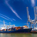 Cargo ship docked at port with cranes unloading.