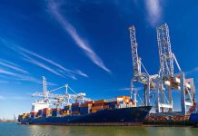 Cargo ship docked at port with cranes unloading.