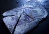 Hundred-dollar bills frozen in cracked ice block.