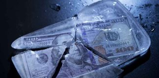 Hundred-dollar bills frozen in cracked ice block.