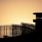 Sunset behind prison fence and guard tower.