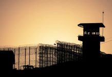 Sunset behind prison fence and guard tower.