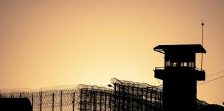 Sunset behind prison fence and guard tower.