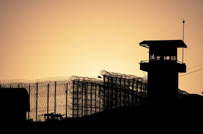 Sunset behind prison fence and guard tower.