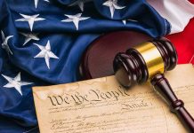 Gavel on U.S. Constitution with American flag background.