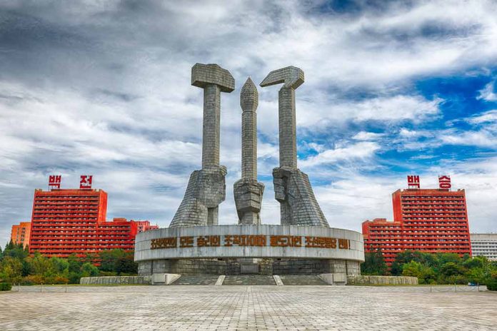 Concrete monument with hands holding tools under cloudy sky.