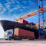 Cargo ship and truck at a busy port.