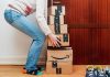 Person stacking Amazon boxes by door.