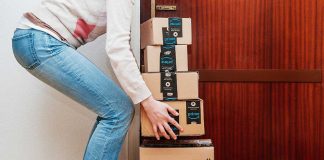 Person stacking Amazon boxes by door.