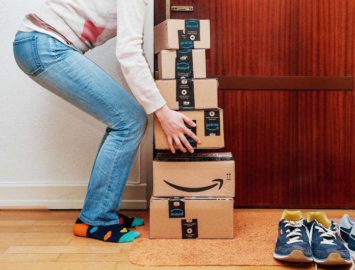 Person stacking Amazon boxes by door.