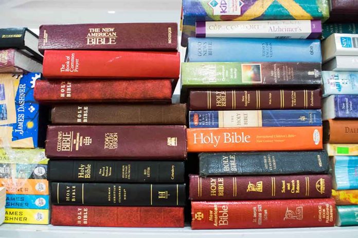 Several Bible editions stacked on a bookshelf.