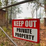 Red Keep Out Private Property sign on gate