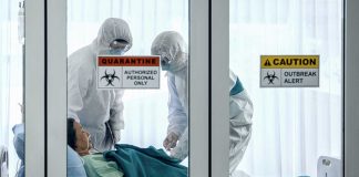 Healthcare workers in protective gear in quarantine room.