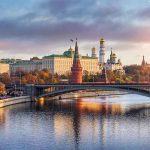 Kremlin by river at sunset with bridge.