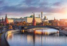 Kremlin by river at sunset with bridge.