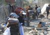 People in makeshift camp with tents and belongings.