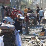 People in makeshift camp with tents and belongings.