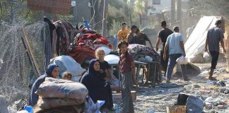 People in makeshift camp with tents and belongings.