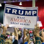 Crowd holding a "Trump Make America Great Again" sign.