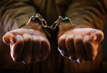 Hands in handcuffs, close-up view.