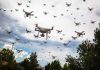 Many drones flying in a cloudy sky.