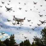 Many drones flying in a cloudy sky.