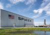 SpaceX building with American flag and launch pad.