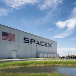 SpaceX building with American flag and launch pad.