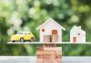 Toy car and houses balanced on stacked coins.