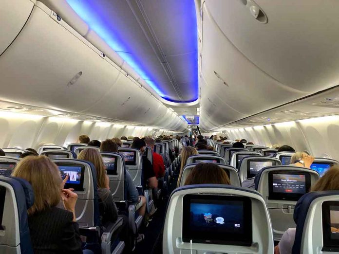 Airplane cabin with passengers and in-flight entertainment screens.