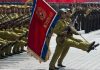 Soldiers marching with flag in military parade.