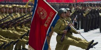 Soldiers marching with flag in military parade.