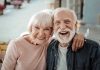 Elderly couple smiling together outdoors.