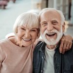 Elderly couple smiling together outdoors.