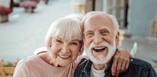 Elderly couple smiling together outdoors.