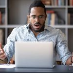 Man surprised while looking at laptop screen.