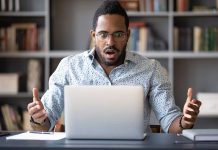 Man surprised while looking at laptop screen.