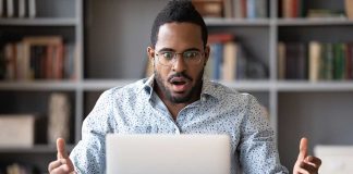 Man surprised while looking at laptop screen.