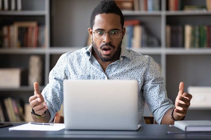 Man surprised while looking at laptop screen.